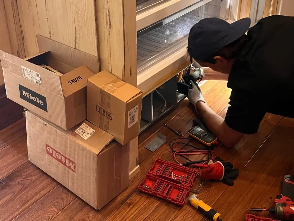 Technician repairing a built-in Miele refrigerator in a Las Vegas kitchen