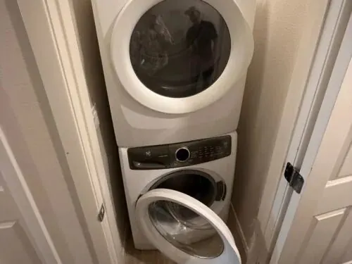 Professional technician diagnosing a stacked Electrolux washer and dryer in a Las Vegas home.
