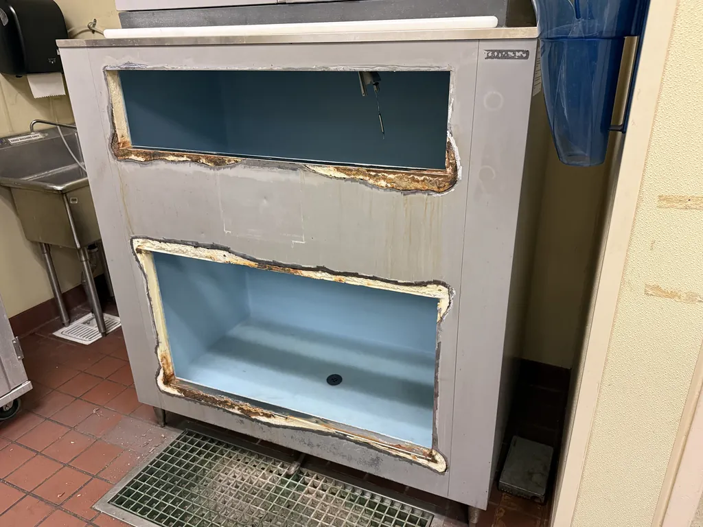 Scotsman ice bin with corroded door frames removed showing rust and wet insulation around the openings