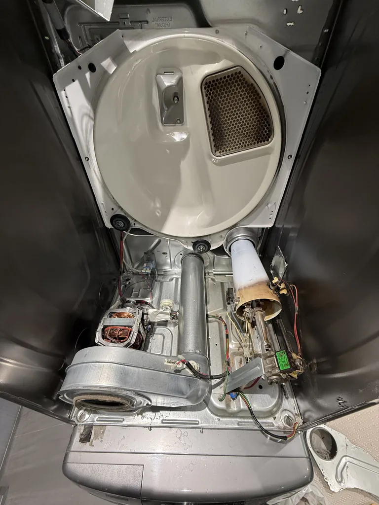 Stacked dryer interior after cleaning with new drum rollers and idler pulley installed
